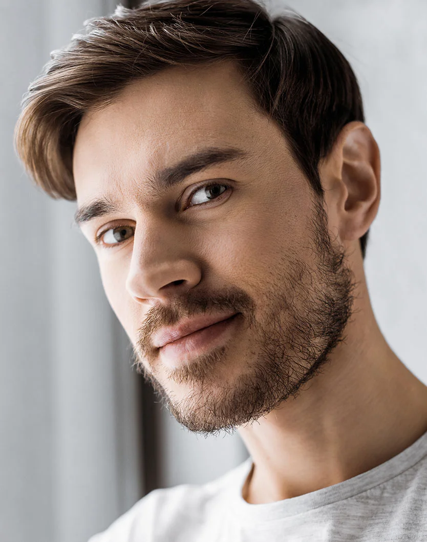 A close-up, friendly portrait of a man with a beard and styled hair, smiling slightly at the camera.